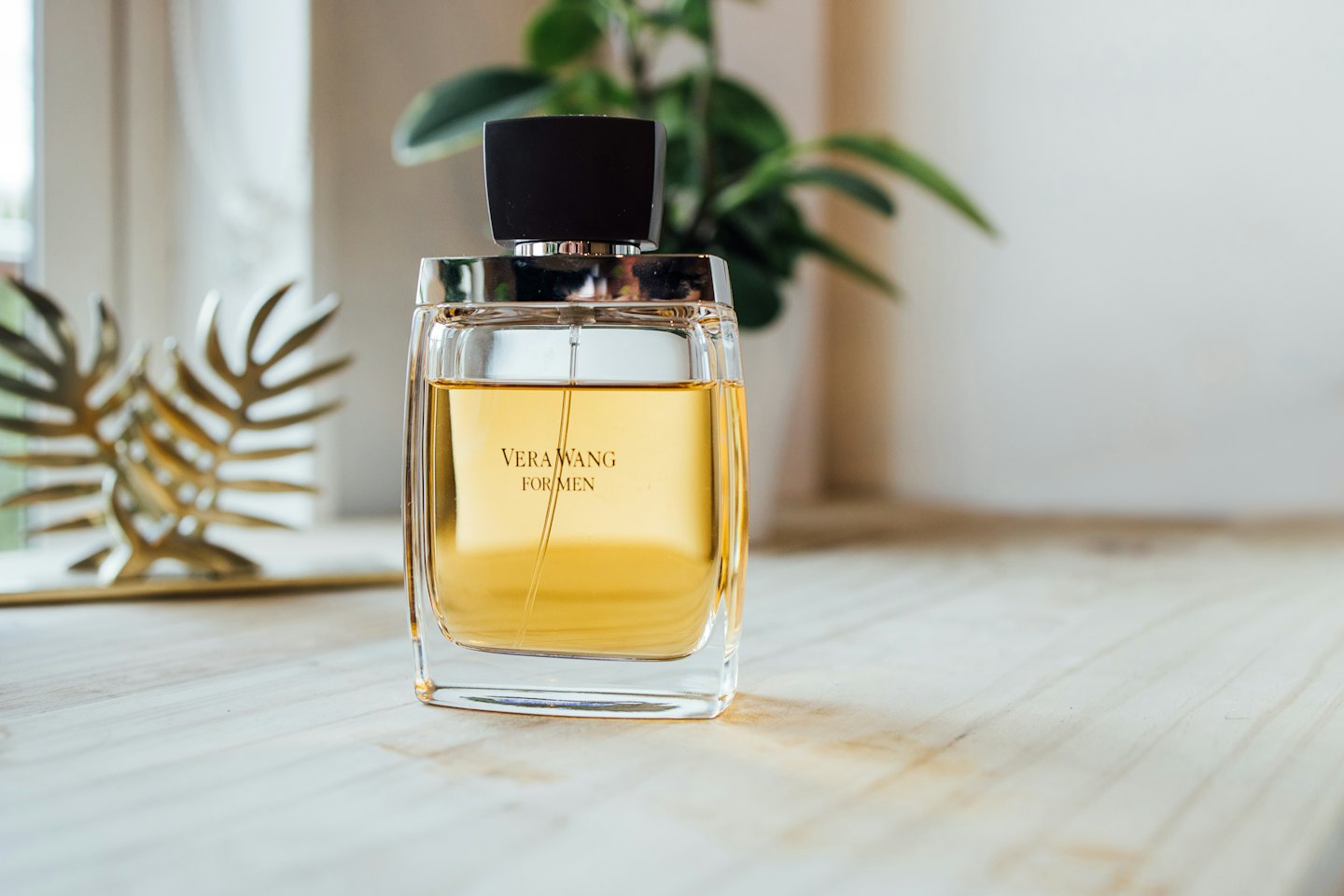 Flacone di profumo in vetro con liquido ambrato su una superficie di legno.