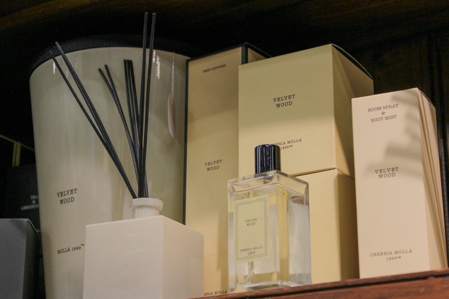 Diffusore per ambienti e boccette di profumo su una mensola di legno.