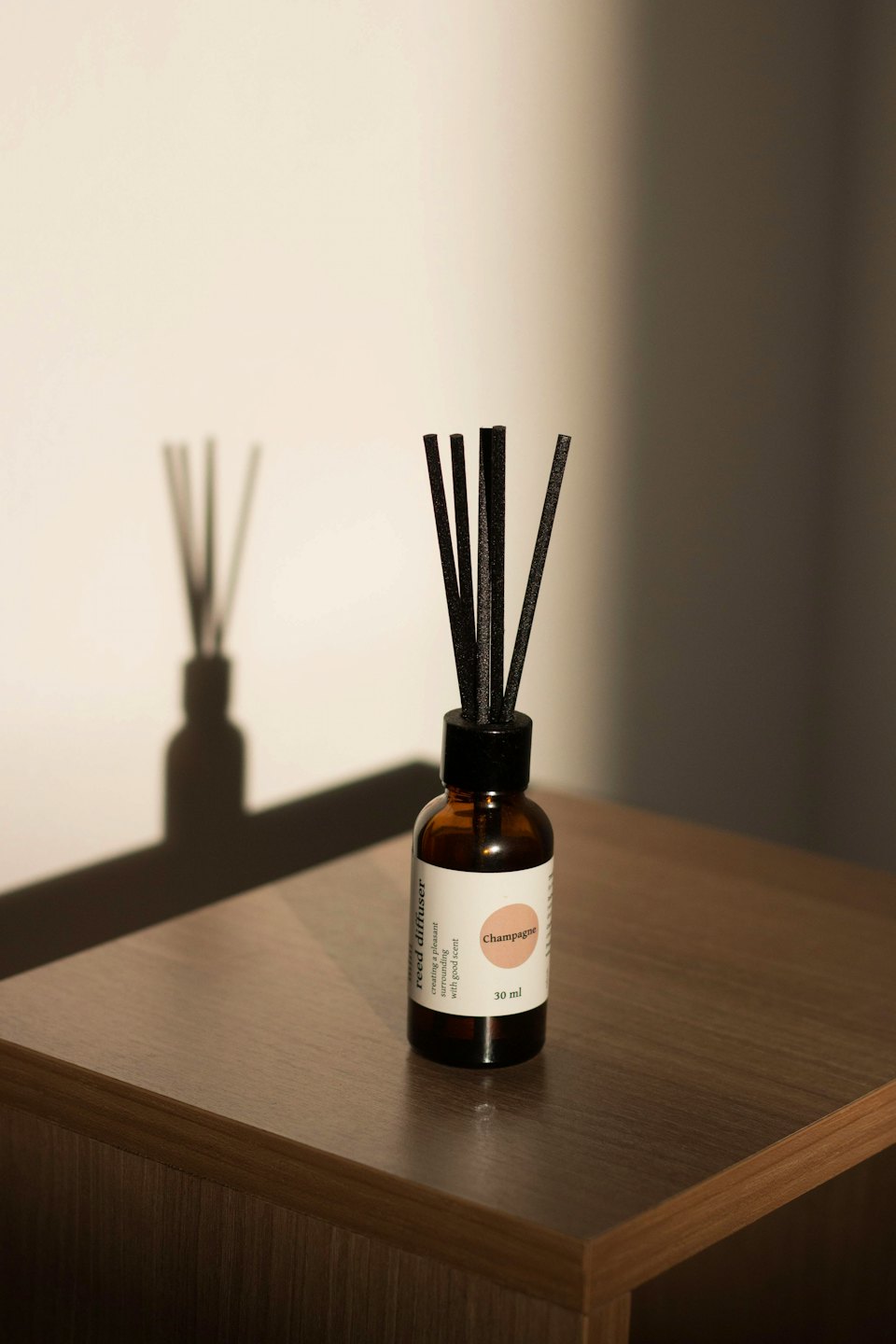 Un diffusore di aromi in vetro ambrato su una superficie di legno scuro.