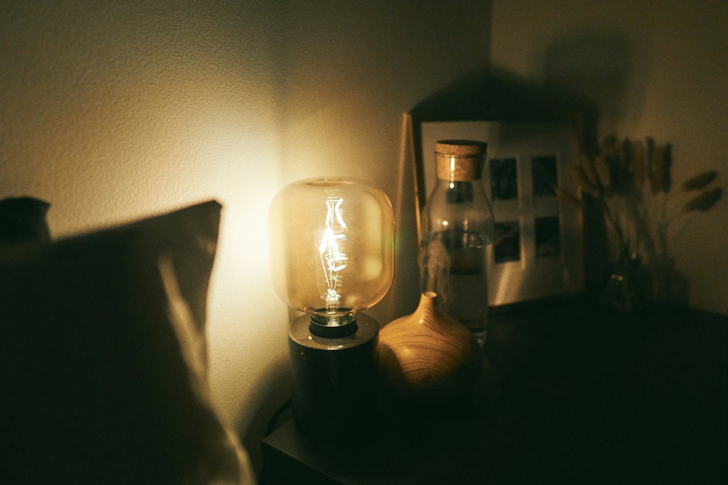 Lampada con lampadina Edison e diffusore di oli essenziali su un comodino.