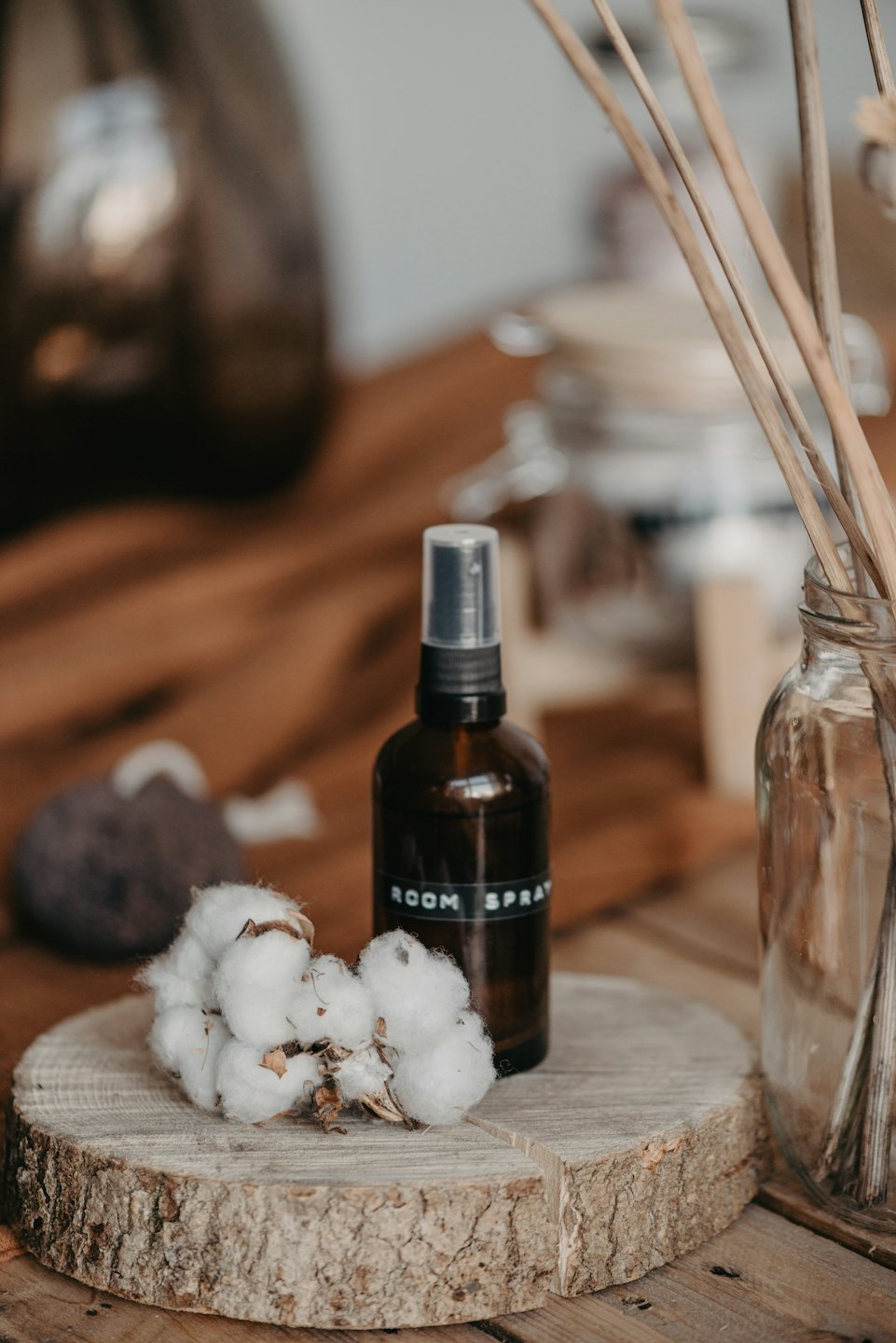 Flacone spray per ambienti e batuffoli di cotone su una lastra di legno.